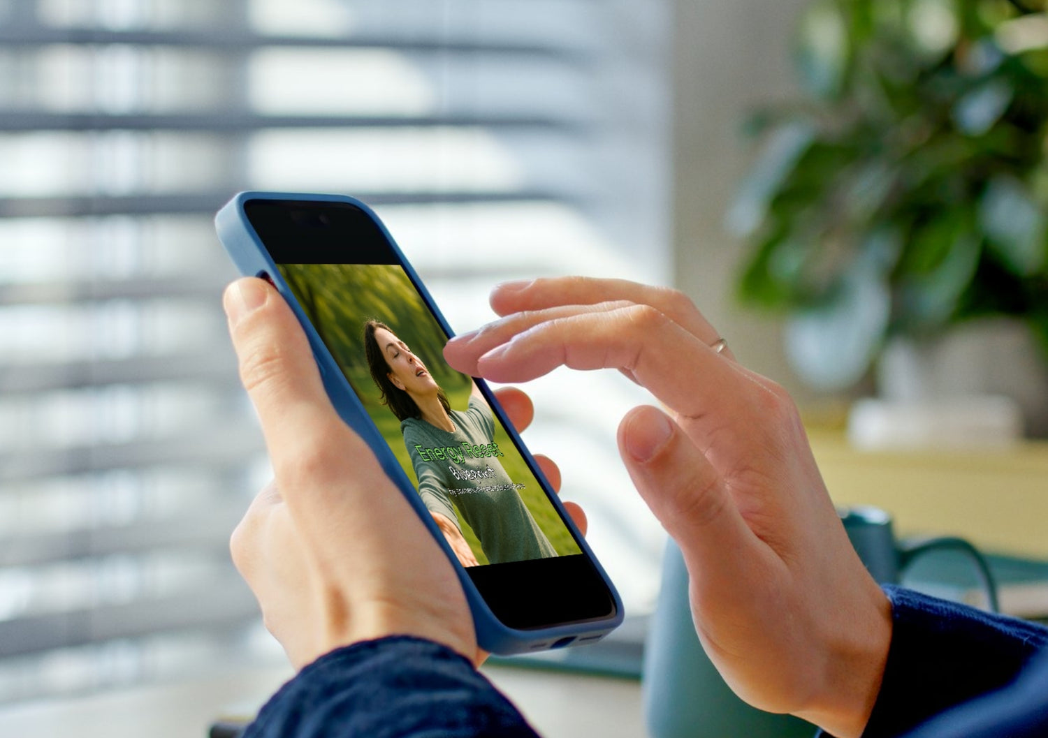 Person holding a smartphone with a photo of a woman on the screen, blurred background. Energy reset blueprint title photo on phone screen.