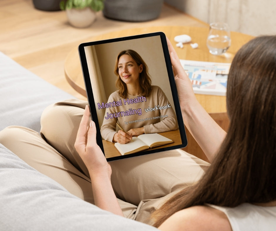 Person holding a tablet with a mental health journaling guide on a living room couch.